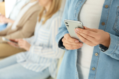 Young woman using modern smartphone indoors, closeup