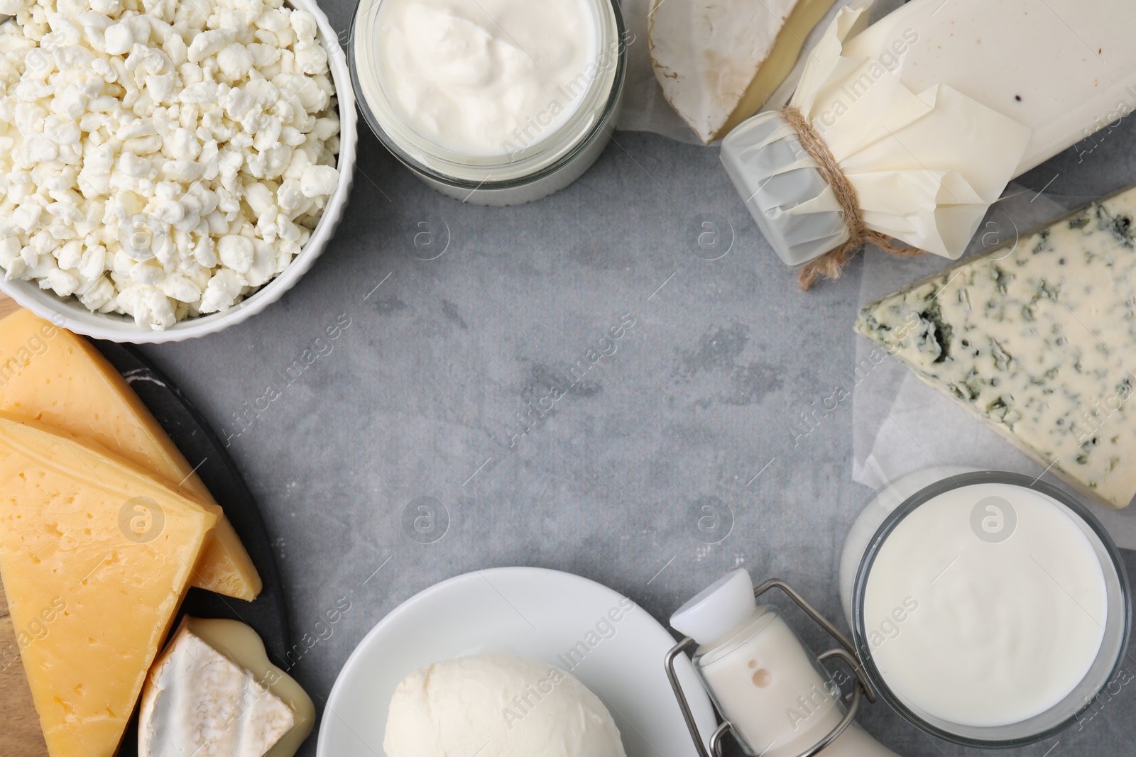 Photo of Frame of different fresh dairy products on grey table, flat lay. Space for text