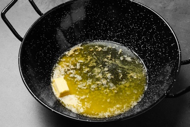 Frying pan with melting butter on grey table, closeup