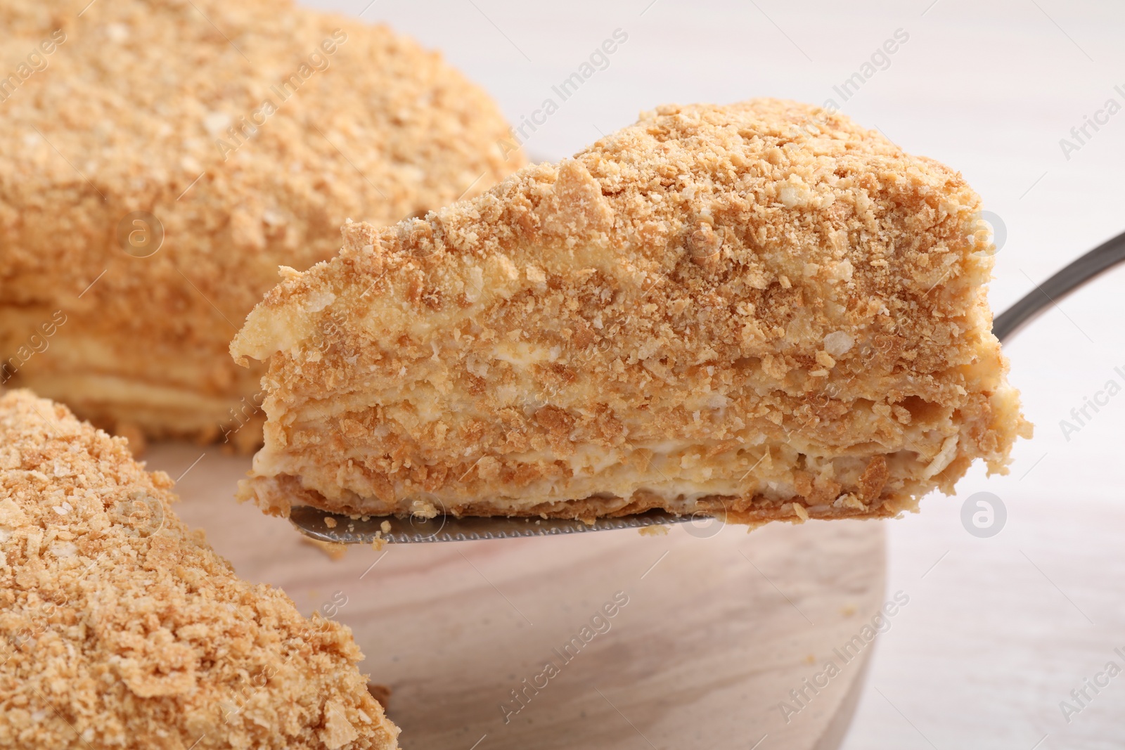 Photo of Taking piece of delicious Napoleon cake from table, closeup