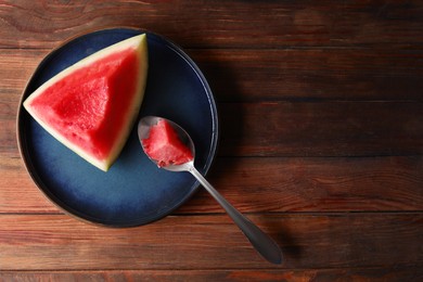 Photo of Sliced fresh juicy watermelon and spoon on wooden table, top view. Space for text