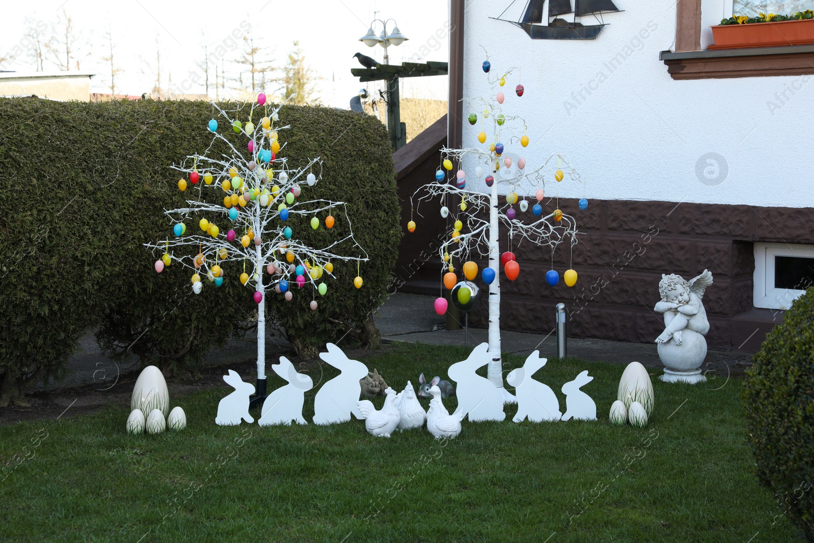 Photo of Trees with decorative eggs, chickens and bunnies at backyard. Easter celebration