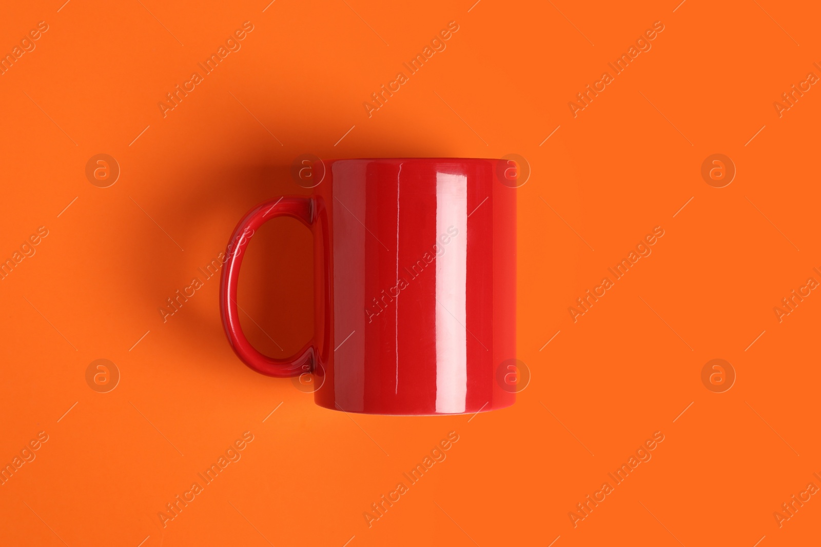 One red ceramic mug on orange background, top view Photo of One red ceramic mug on orange background, top view