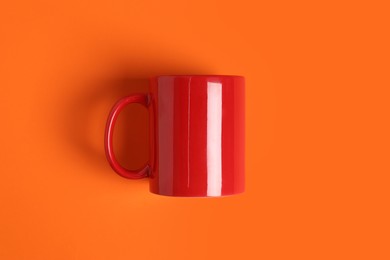 Photo of One red ceramic mug on orange background, top view