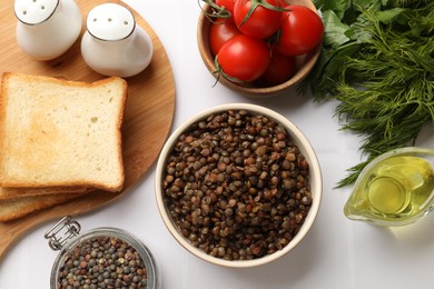 Photo of Delicious lentils in bowl served on white table, flat lay