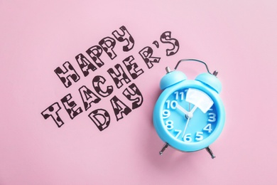Photo of Alarm clock and text HAPPY TEACHER'S DAY on color paper