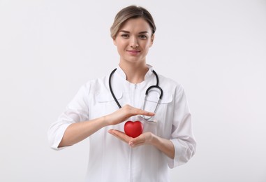 Doctor with stethoscope and red heart on white background. Cardiology concept