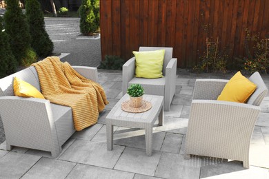 Photo of Beautiful rattan garden furniture, soft pillows, blanket and houseplant in backyard