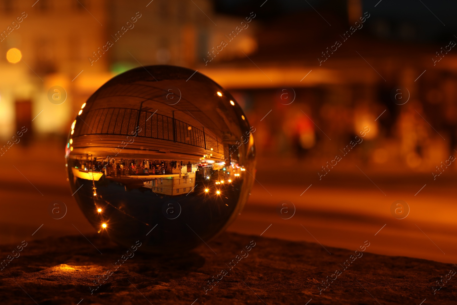 Photo of Beautiful city street, overturned reflection. Crystal ball at night, closeup. Space for text