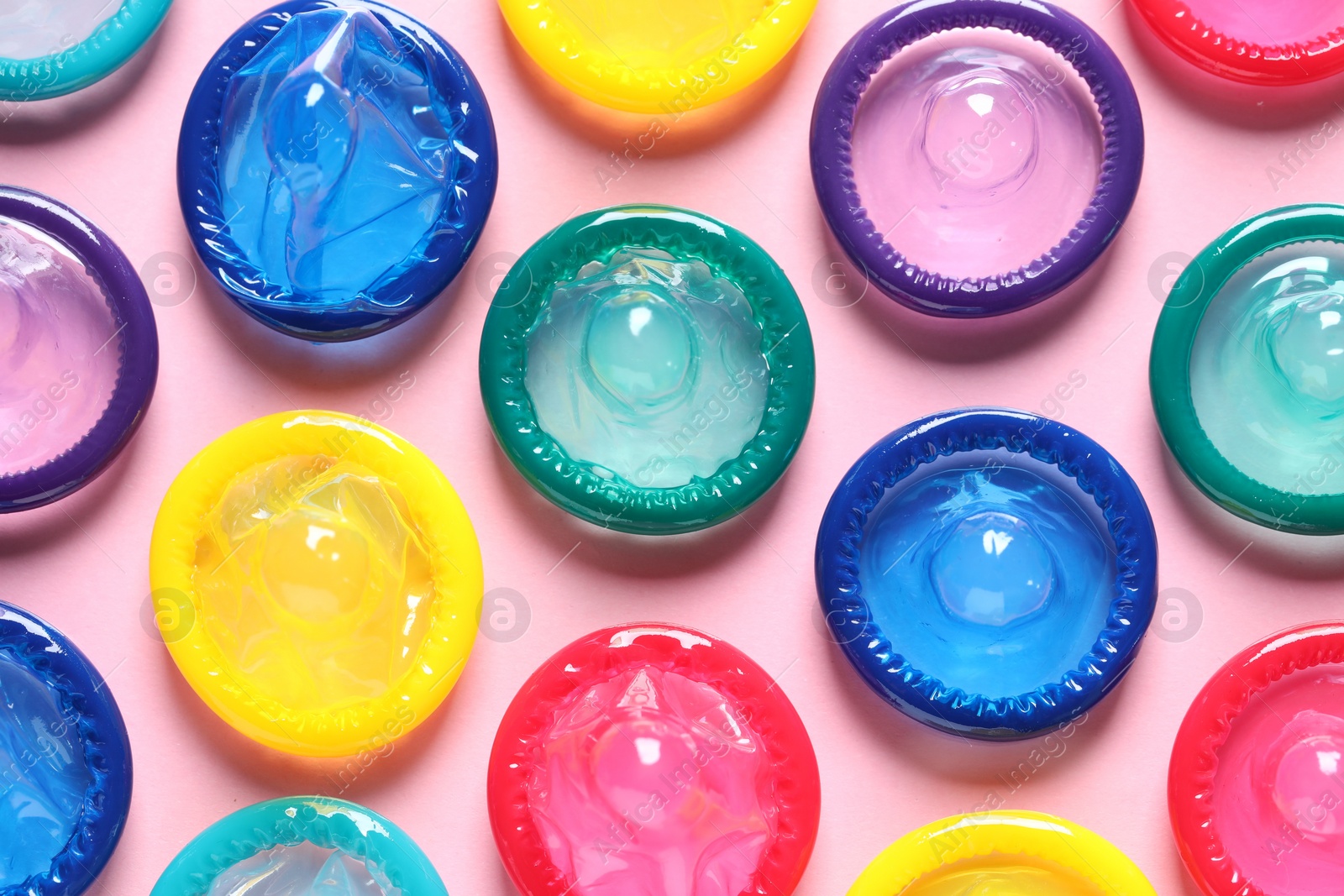 Photo of Colorful condoms on pink background, flat lay