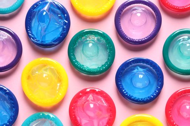 Photo of Colorful condoms on pink background, flat lay