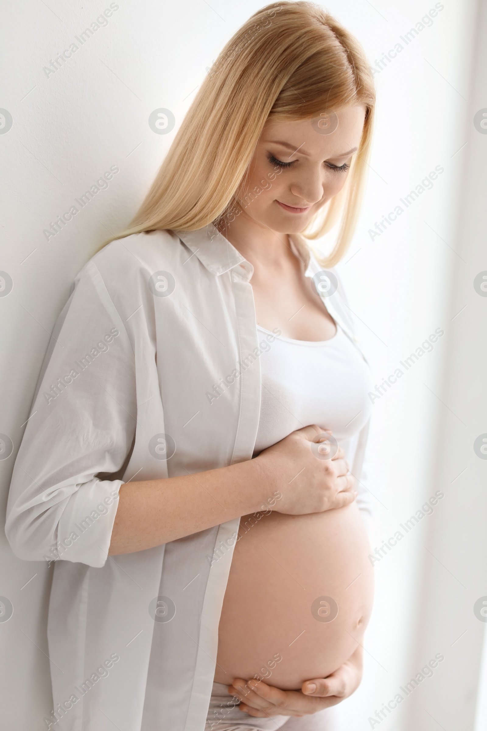 Photo of Portrait of beautiful pregnant woman near light wall