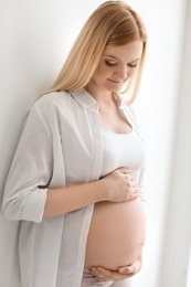 Photo of Portrait of beautiful pregnant woman near light wall