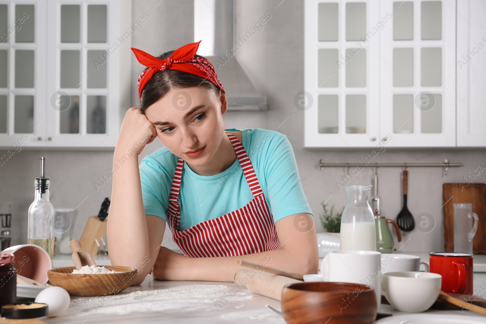 Photo of Upset housewife at messy countertop in kitchen. Many dirty dishware, food leftovers and utensils on table