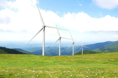 Image of Alternative energy source. Wind turbines in mountains under cloudy sky