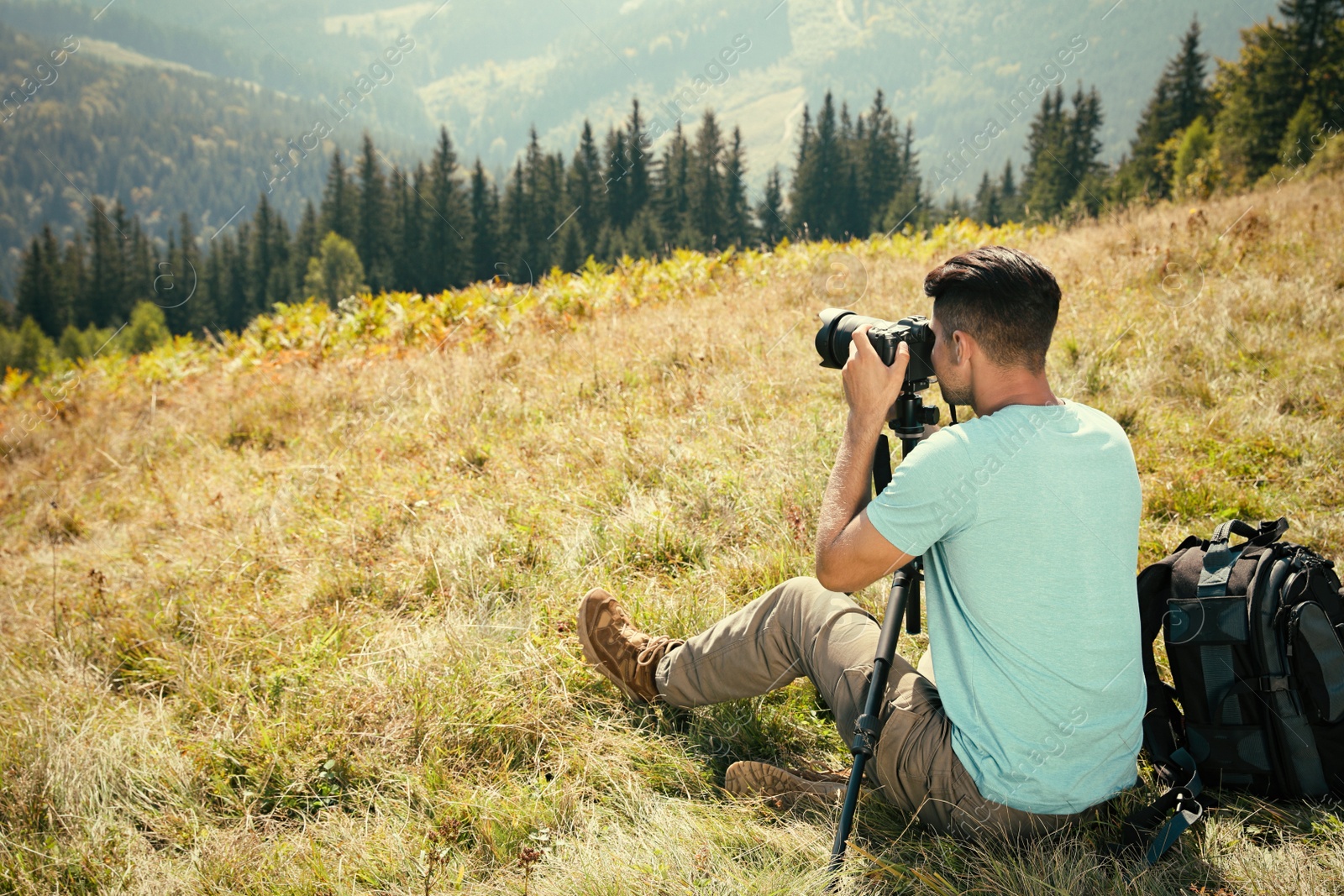 Photo of Professional photographer taking picture with modern camera in mountains. Space for text