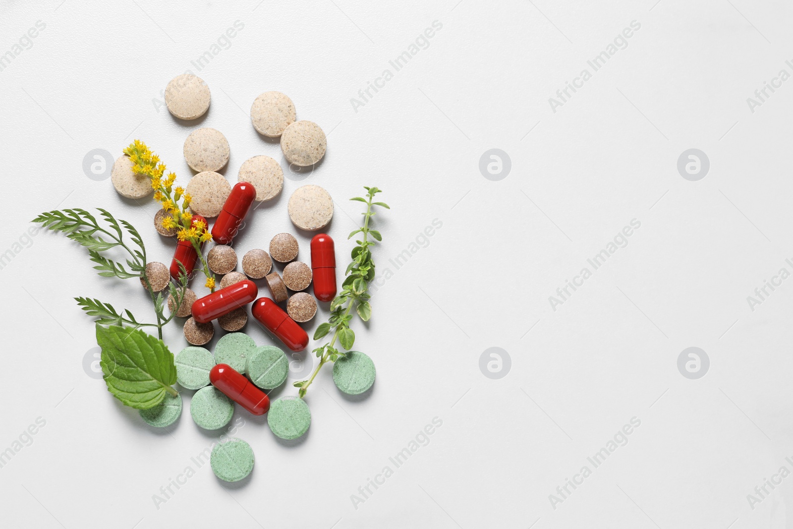 Photo of Different pills and herbs on white table, flat lay with space for text. Dietary supplements