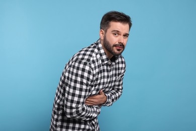 Photo of Man suffering from stomach pain on light blue background