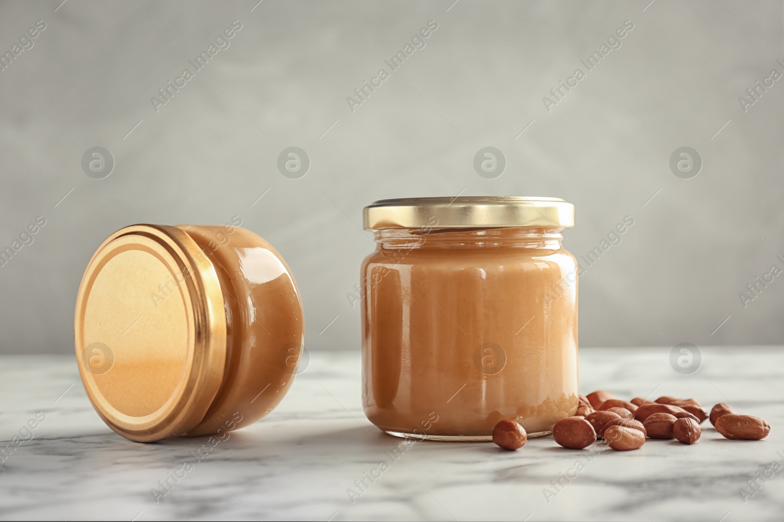 Photo of Jars with creamy peanut butter on table