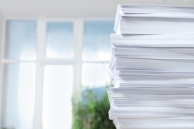 Stack of paper sheets against blurred background, closeup. Space for text