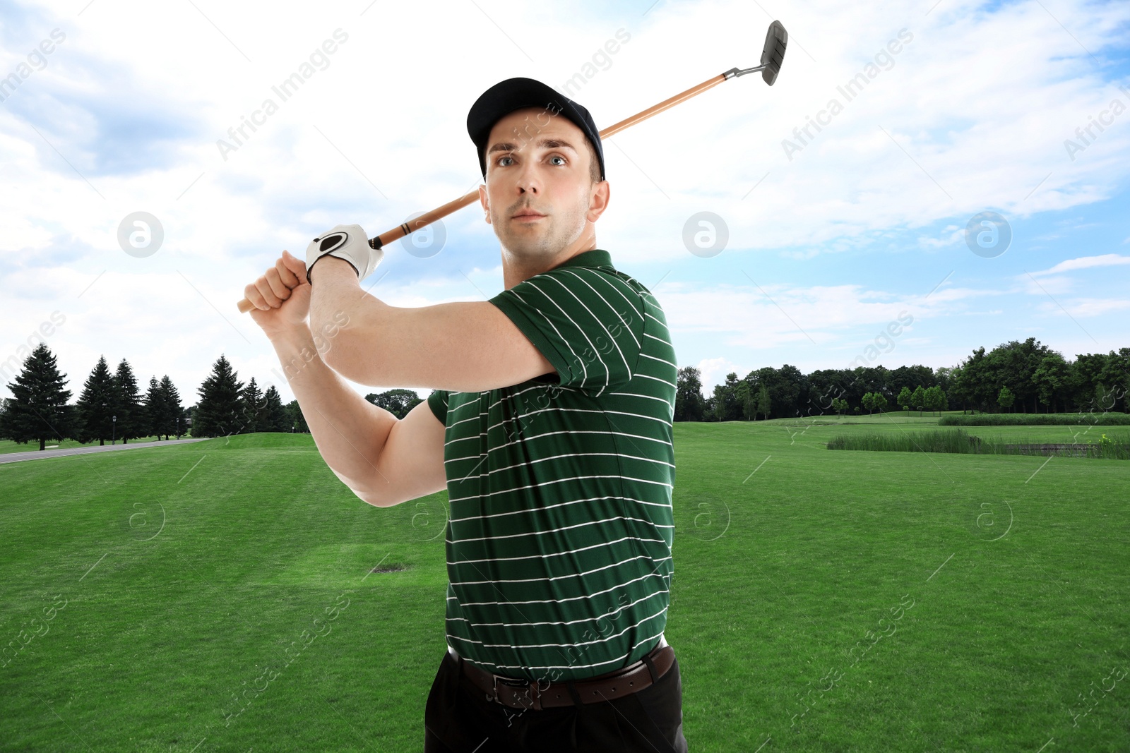 Image of Young man playing golf on course with green grass