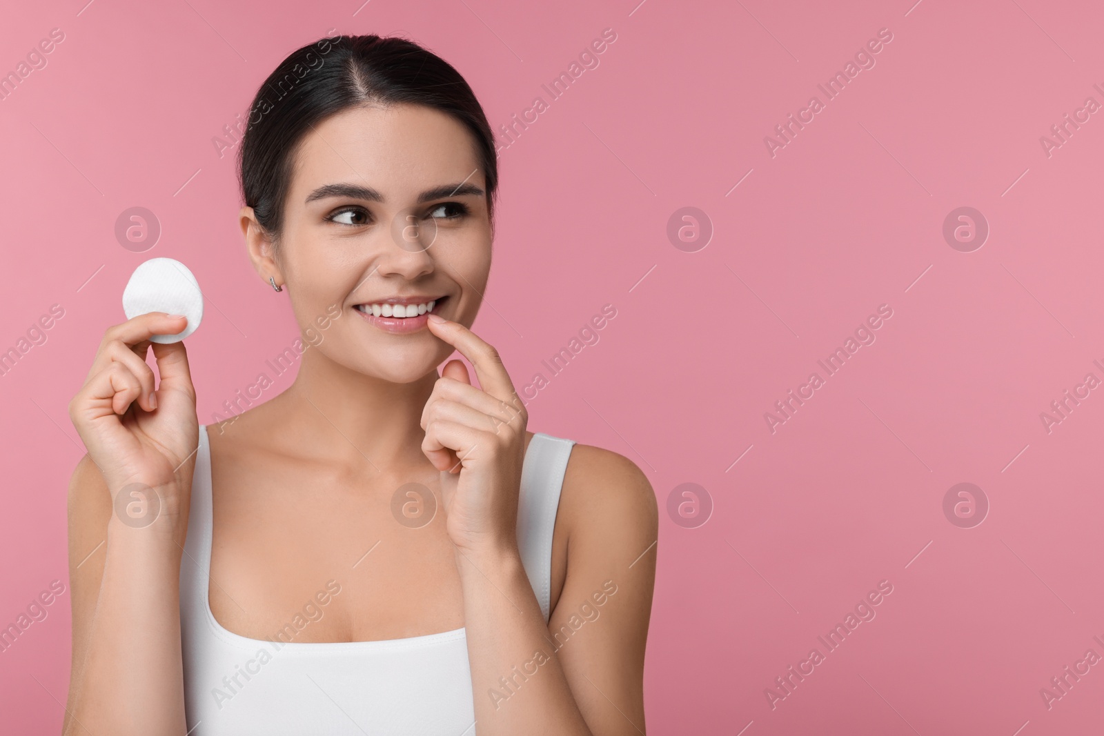 Photo of Young woman with cotton pad on pink background. Space for text