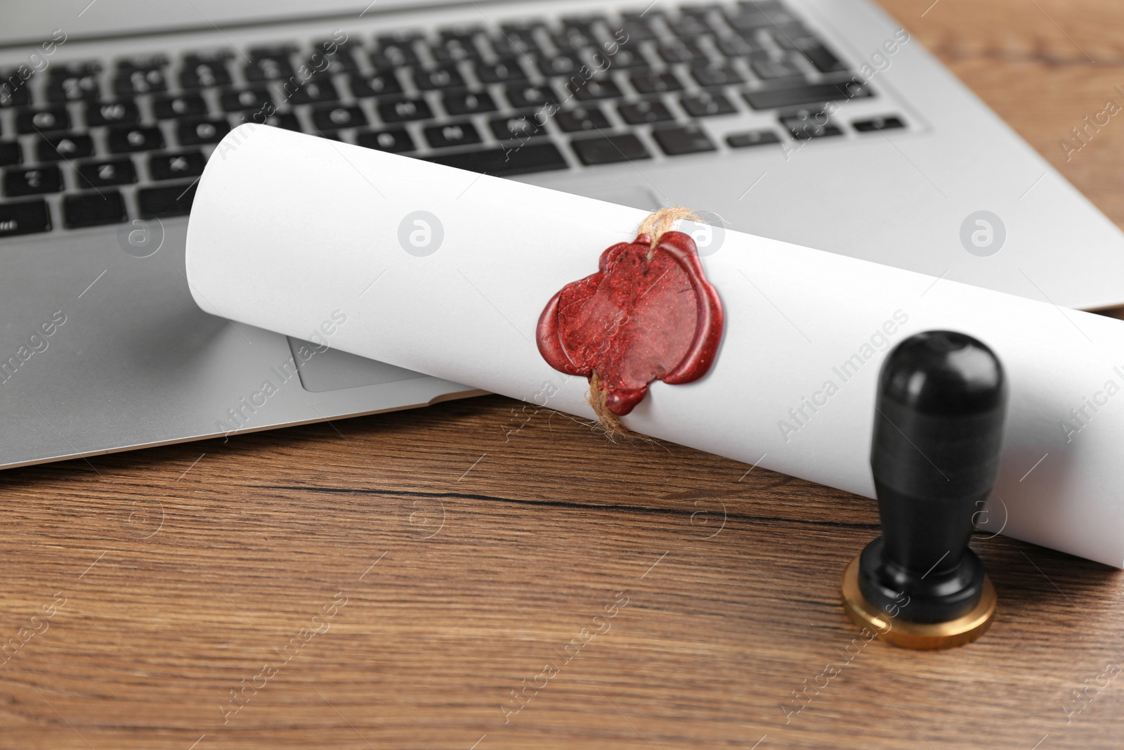 Photo of Notary's public pen and sealed document near laptop on wooden table, closeup