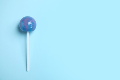 Photo of Stick with bright lollipop on light blue background, top view. Space for text