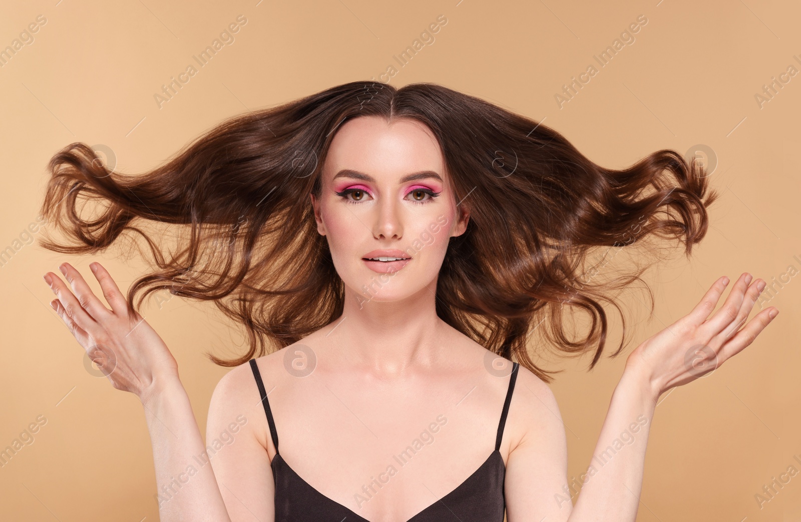 Photo of Portrait of beautiful young woman with makeup and gorgeous hair styling on beige background