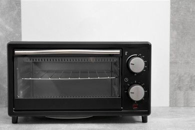 Photo of One electric oven on light grey table. Cooking appliance