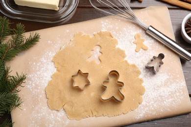 Photo of Making Christmas cookies. Flat lay composition with cutters and raw dough on wooden table