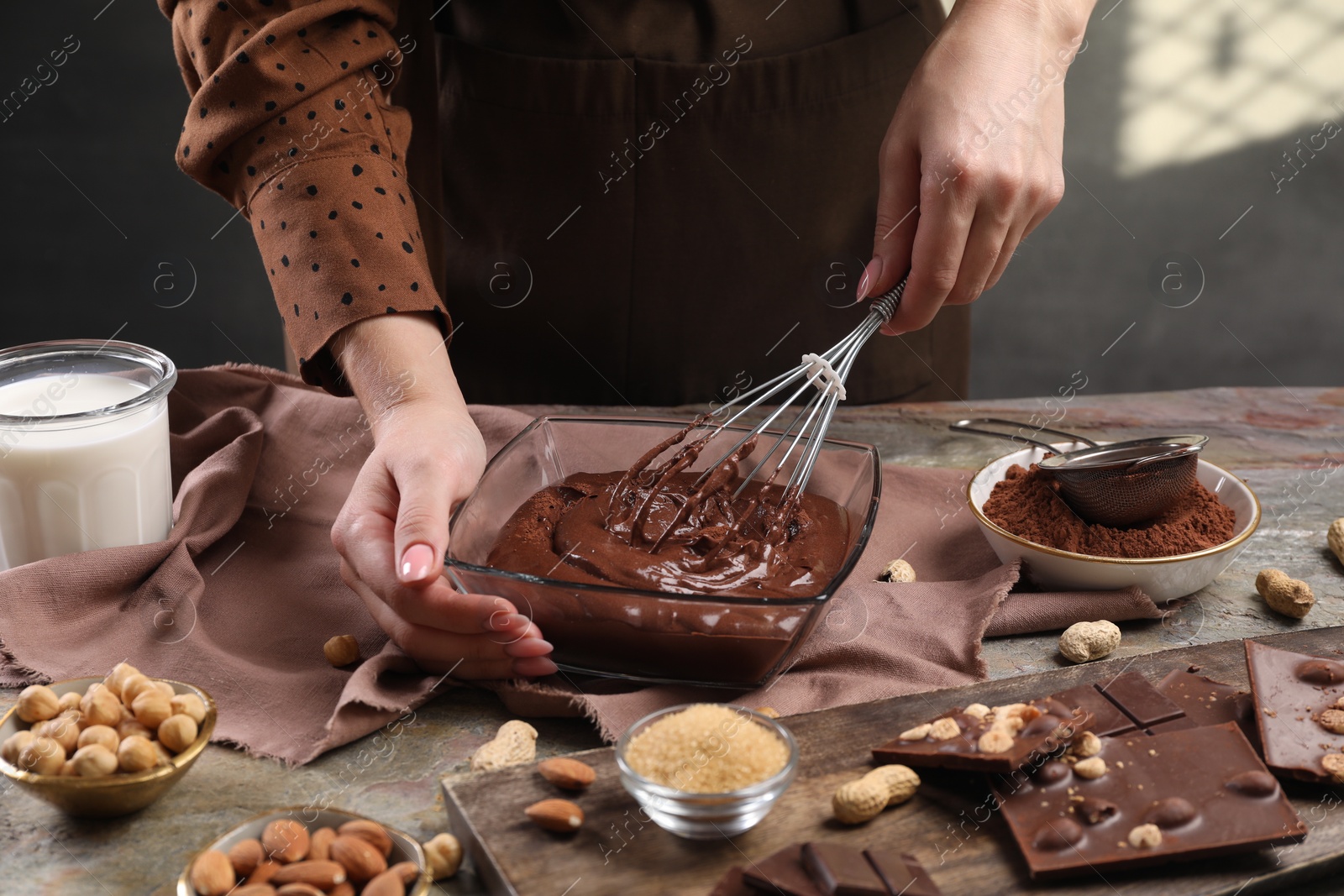 Photo of Woman mixing delicious chocolate cream with whisk at table, closeup