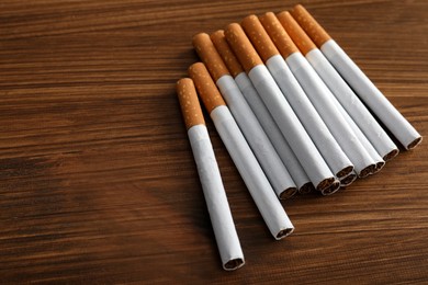 Pile of cigarettes on wooden table. Space for text