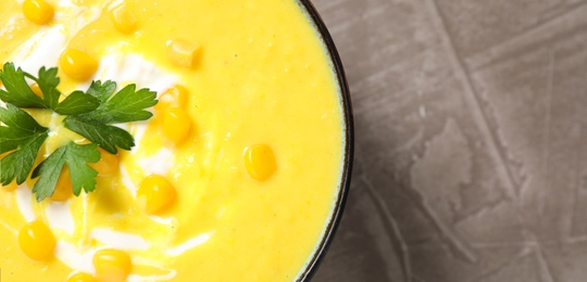 Photo of Delicious creamy corn soup served on grey table, top view