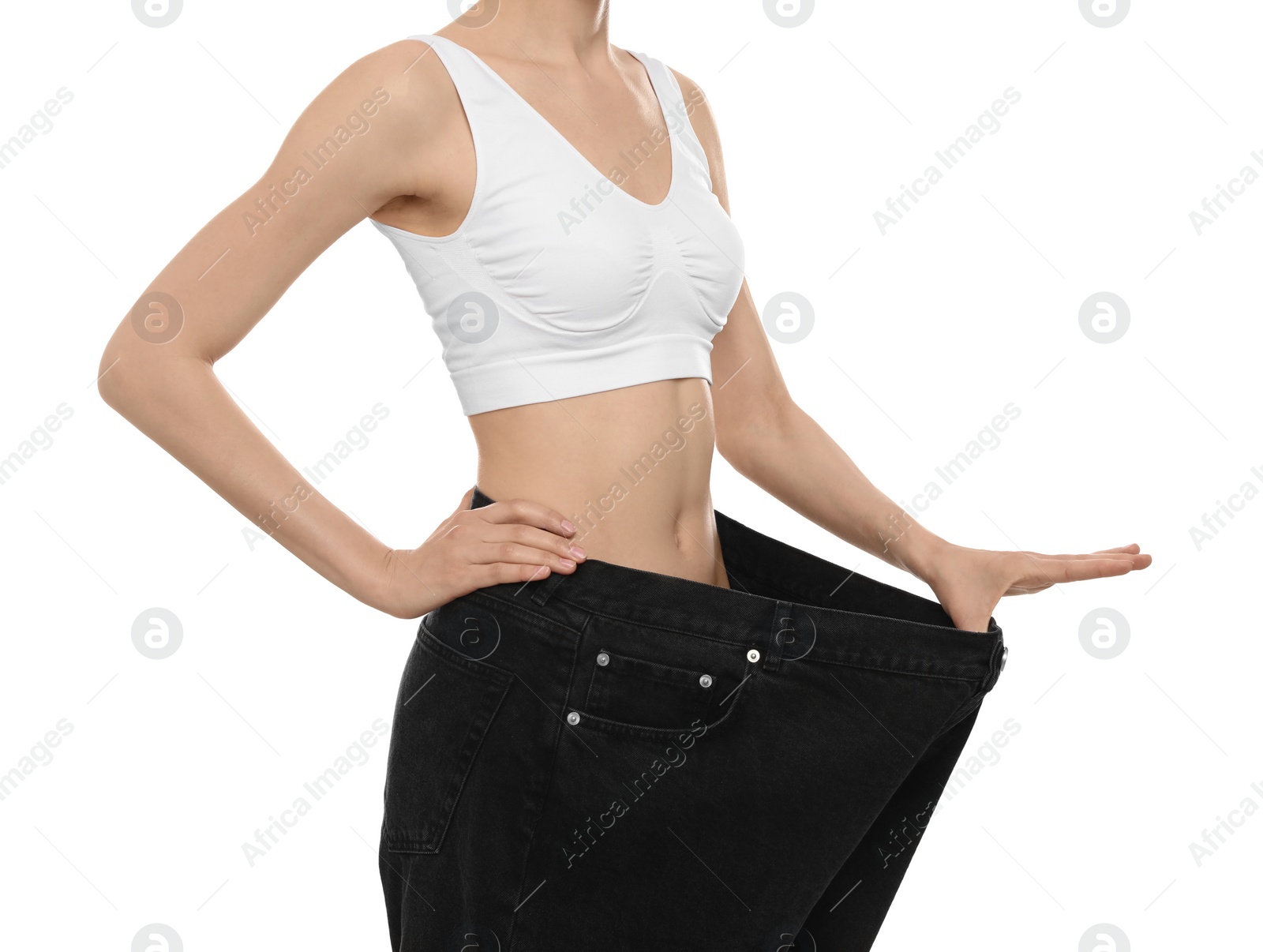 Photo of Young woman wearing big jeans after weight loss on white background, closeup