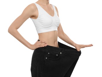 Photo of Young woman wearing big jeans after weight loss on white background, closeup