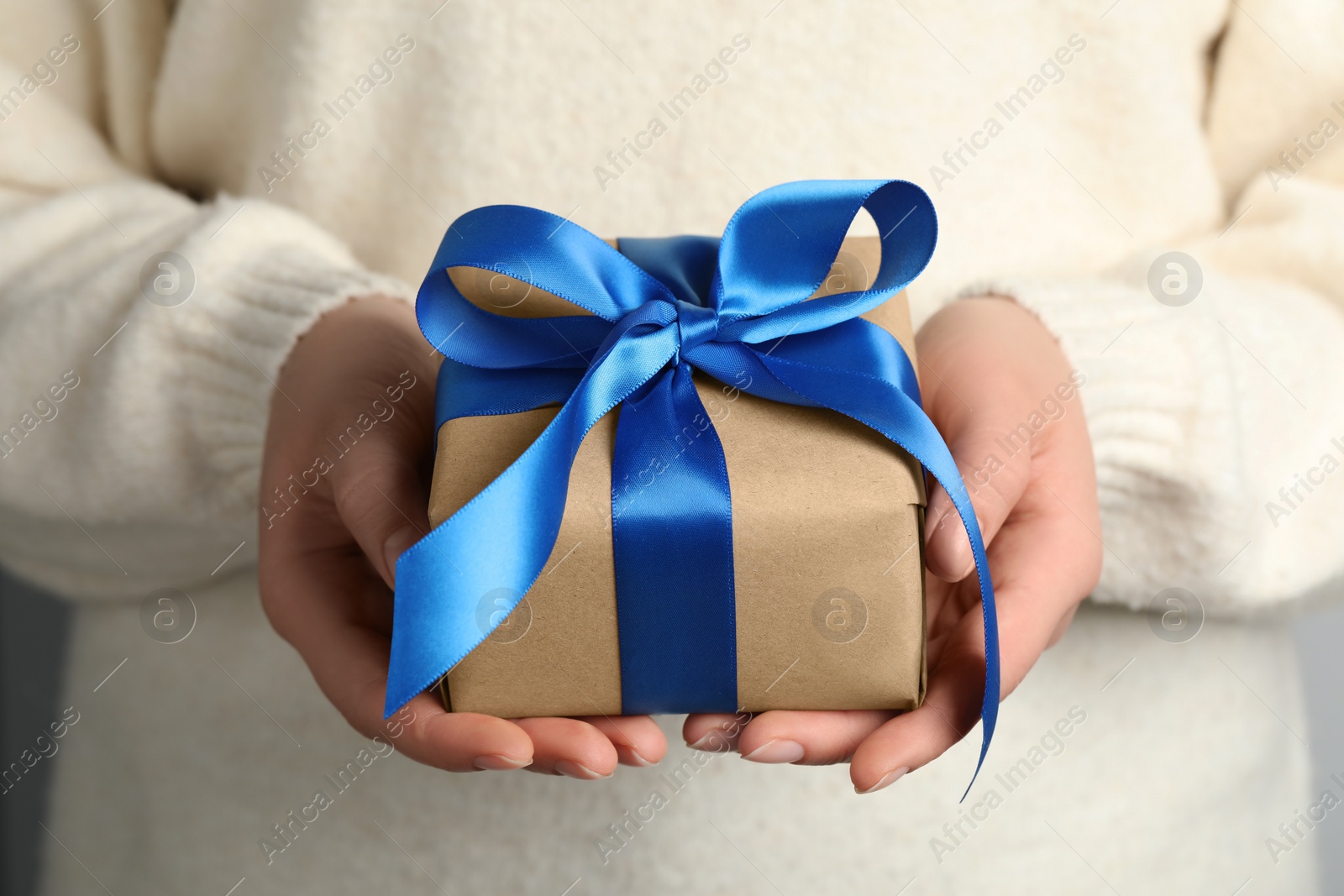 Photo of Woman holding gift box with blue bow, closeup