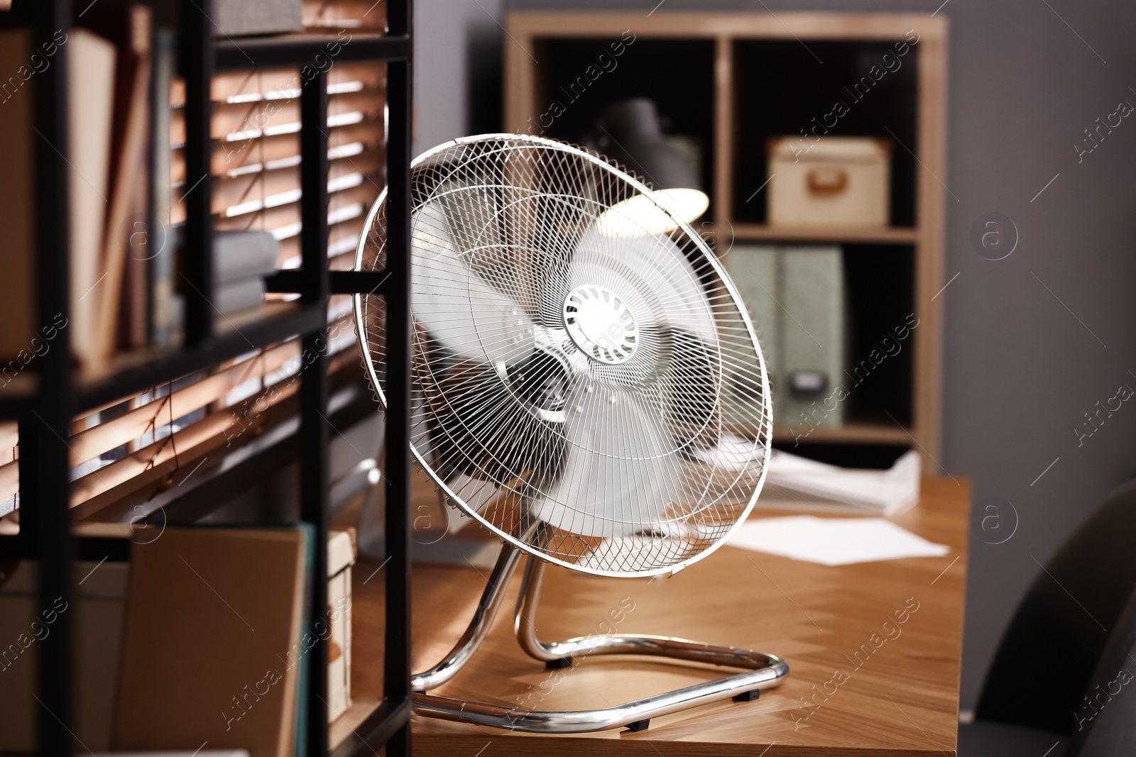 Photo of Modern electric fan on table in office