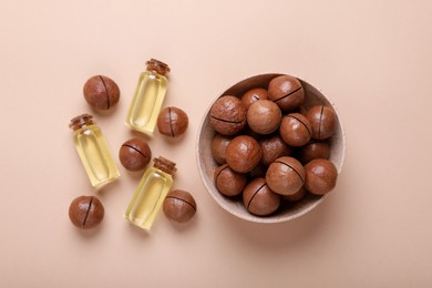 Delicious organic Macadamia nuts and cosmetic oil on beige background, flat lay