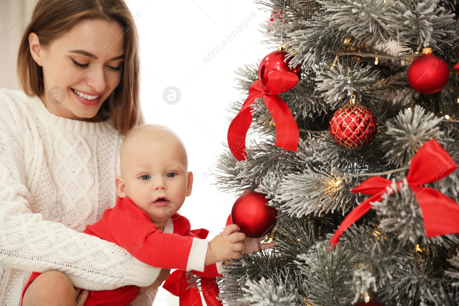 Photo of Happy mother with cute baby near Christmas tree at home