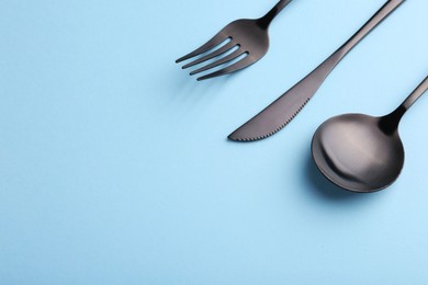 Stylish cutlery set on light blue table, closeup. Space for text