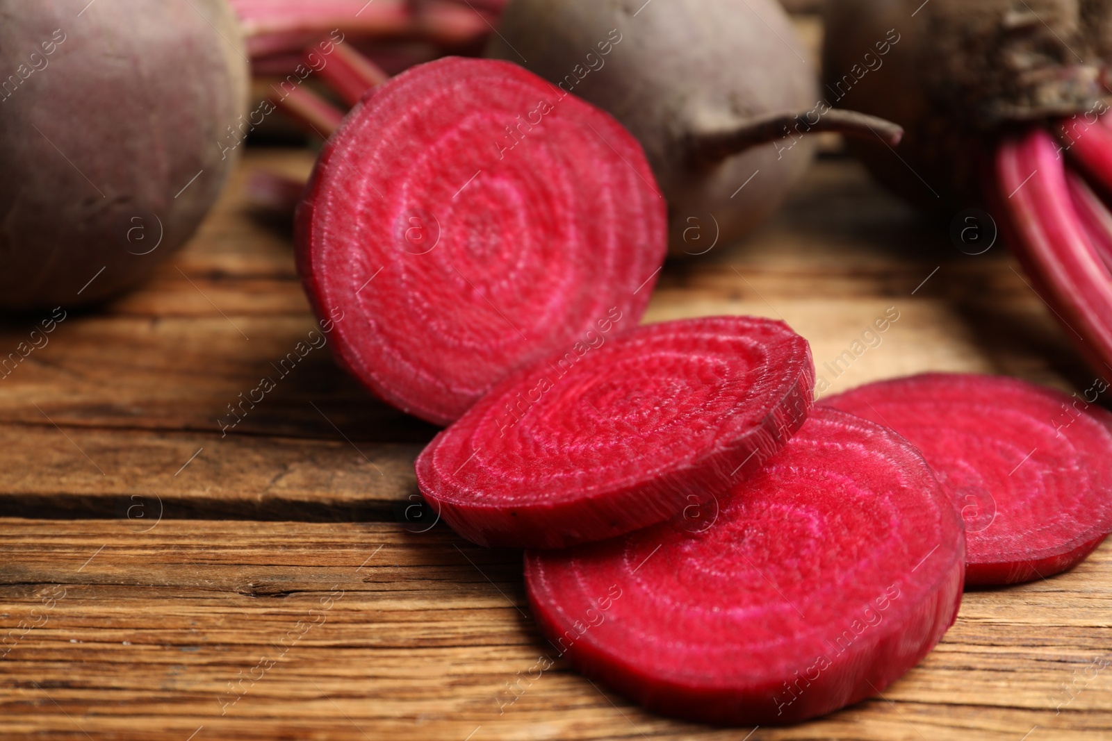 Photo of Cut raw beet on wooden table, closeup