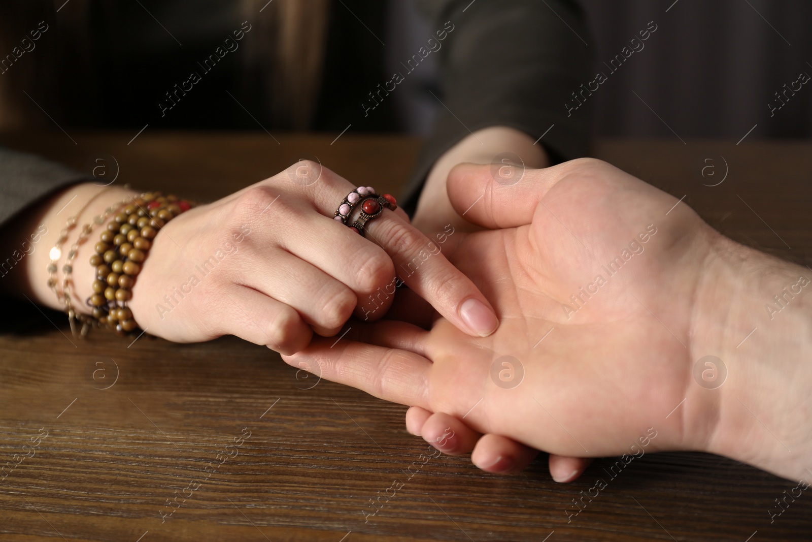 Photo of Chiromancer reading lines on man's palm at table, closeup