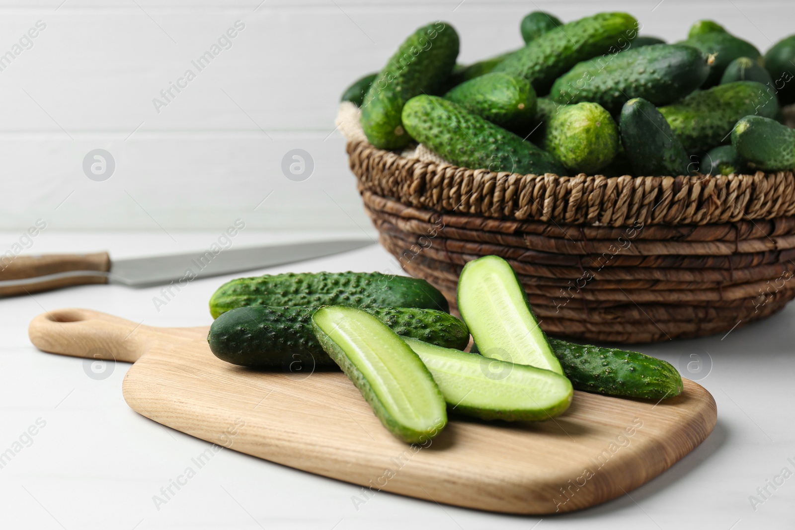 Photo of Whole and cut fresh ripe cucumbers on white table