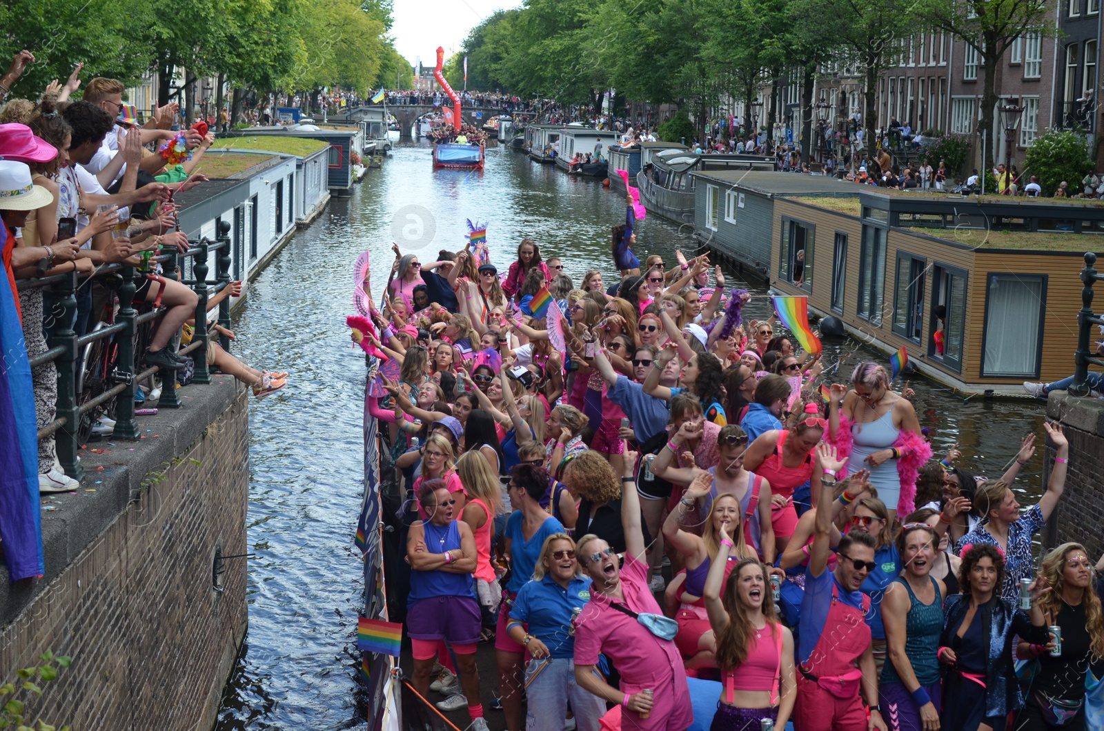 Photo of AMSTERDAM, NETHERLANDS - AUGUST 06, 2022: Many people in boats at LGBT pride parade on river