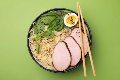Photo of Delicious ramen with meat on light green background, top view. Noodle soup