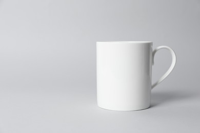 Photo of White ceramic mug on light grey background. Space for text