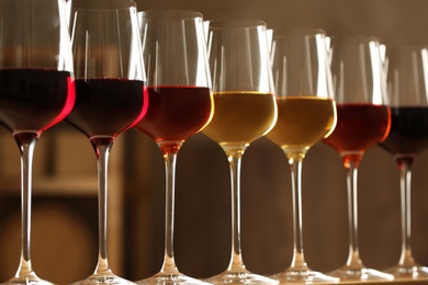 Photo of Glasses of different wines against blurred background. Expensive collection