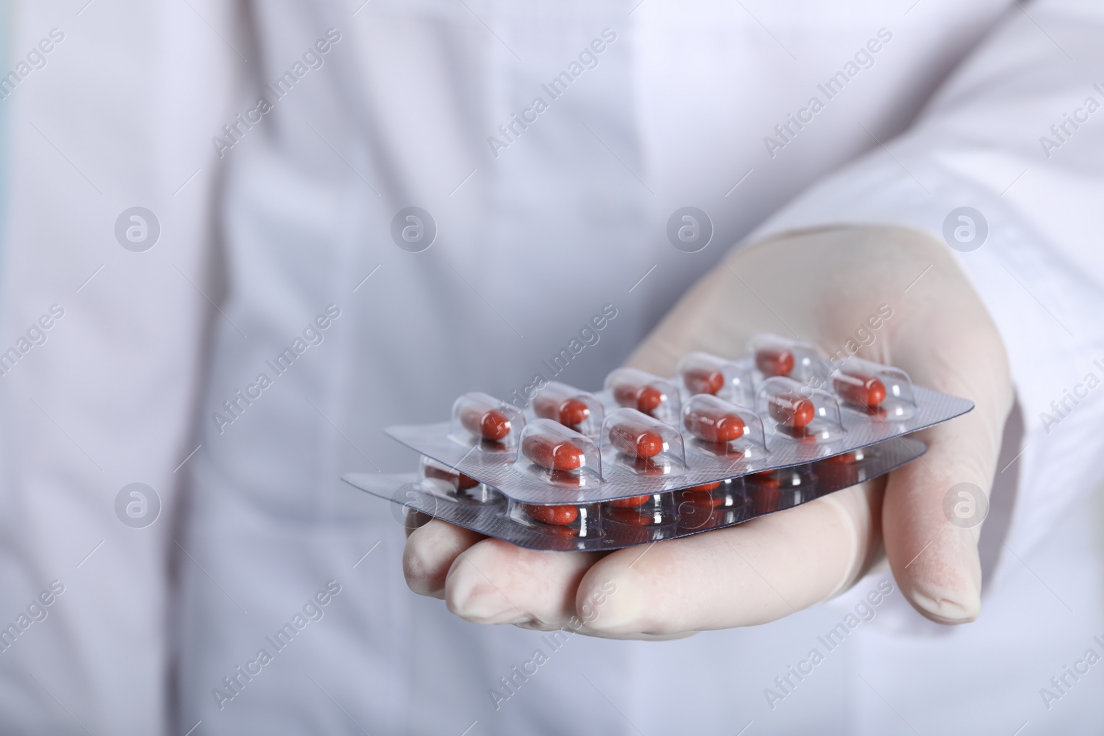 Photo of Doctor holding red pills, closeup and space for text. Anemia treatment