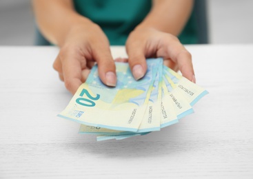 Woman with Euro banknotes at table, closeup